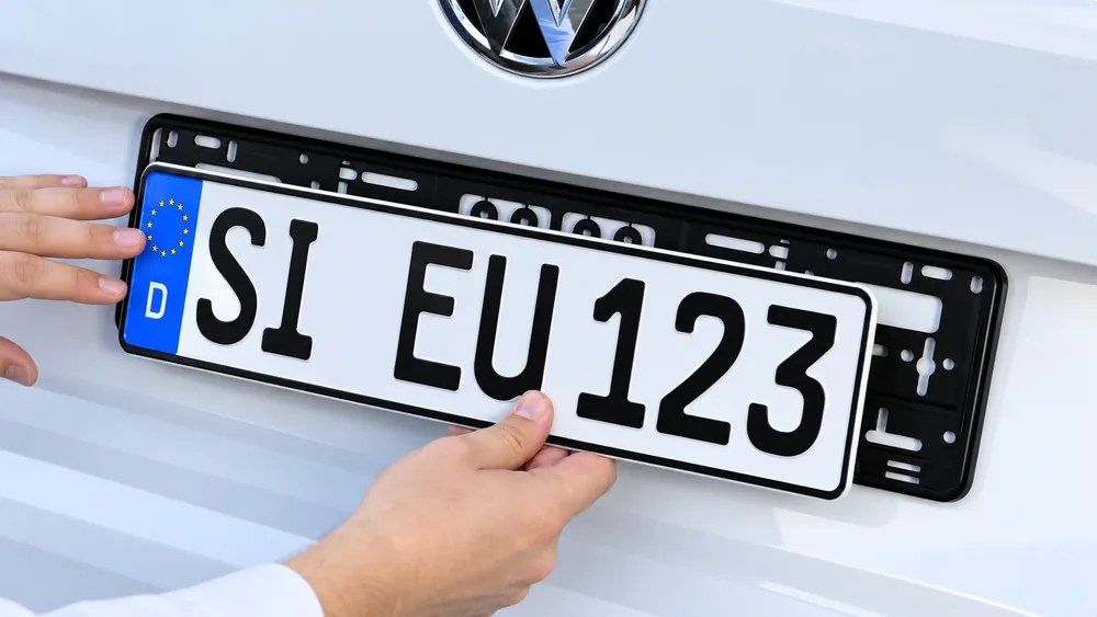 Kfz-Kennzeichen in den montierten Kennzeichenhalter einsetzen